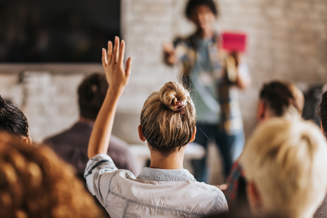 woman raising her hand in class